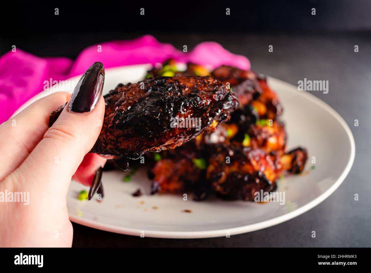 Hand Holding Up a Sticky Glazed Chicken Wing Closeup view of a
