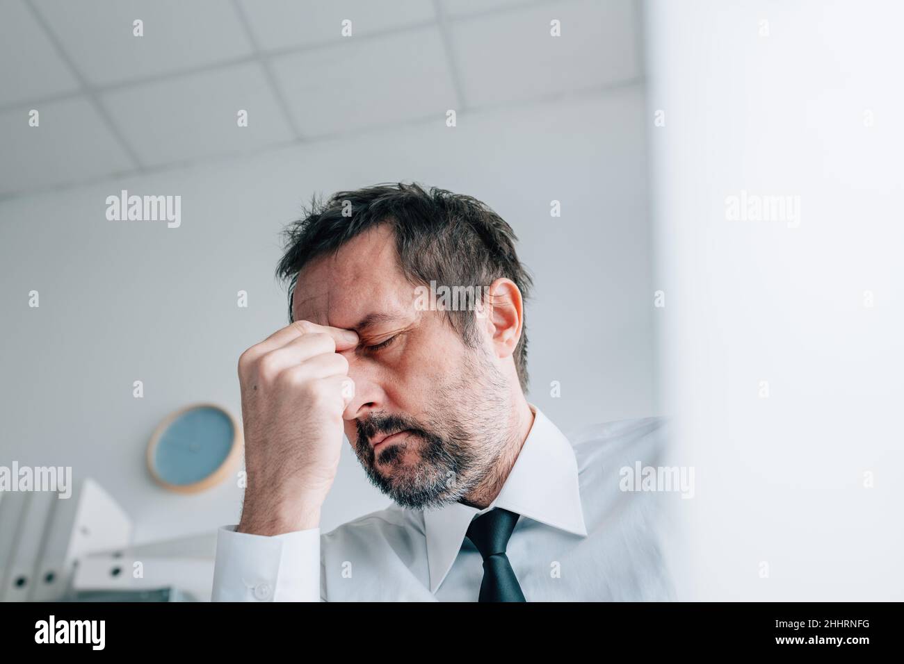 Business owner headache concept, businessman with painful migraine in office, selective focus Stock Photo