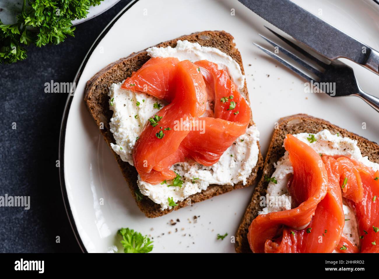 Rye bread toast with cream cheese and salmon on a plate top view. Healthy appetizer or snack open sandwiches Stock Photo