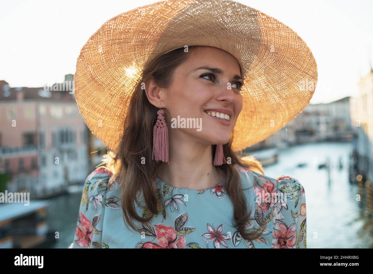happy young solo tourist woman in floral dress with hat sightseeing on Accademia bridge in Venice, Italy. Stock Photo