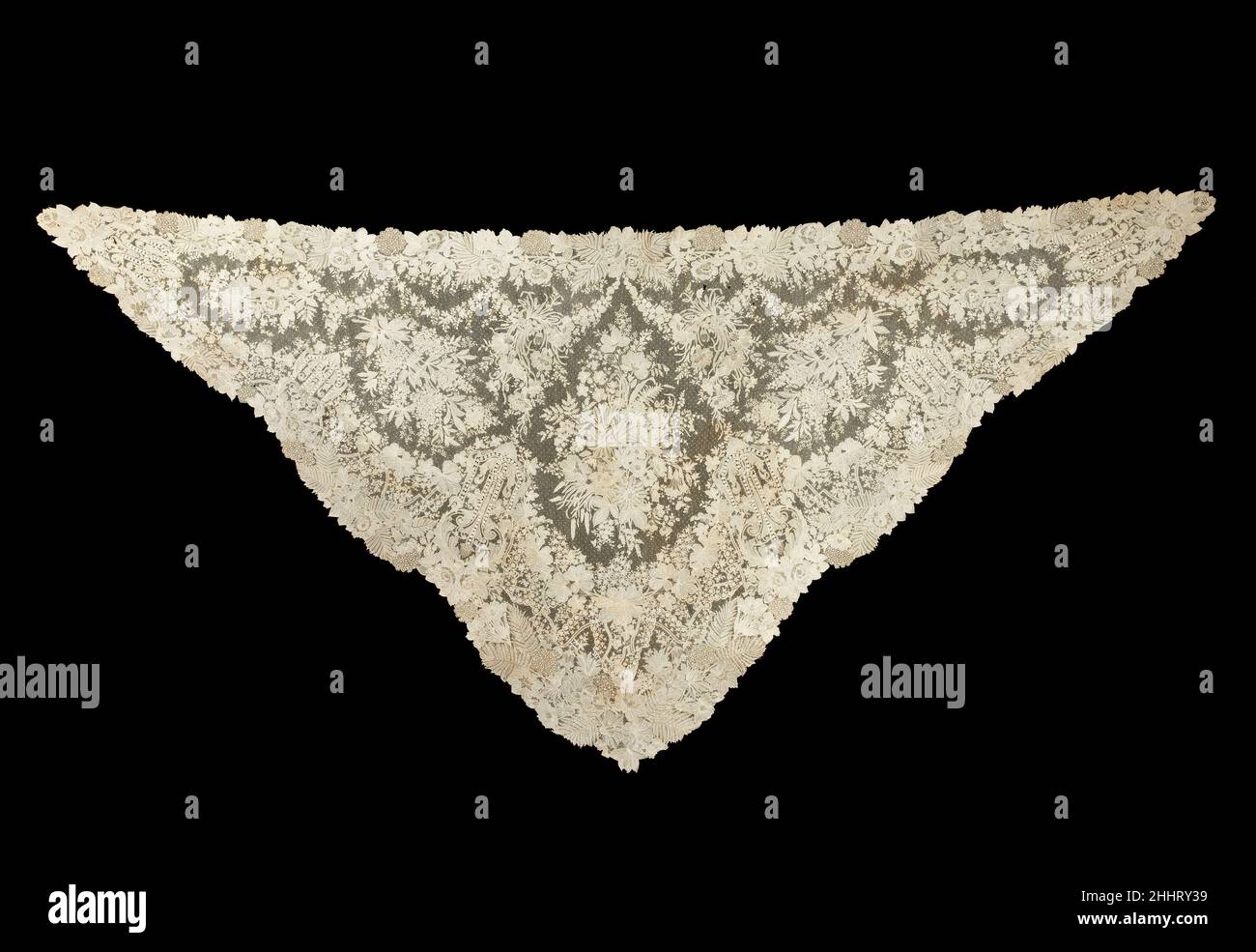 Shawl third quarter 19th century Belgian The high quality of this Brussels needle lace shawl is displayed not only in the fine workmanship but also in the complexity of its design. The variety of motifs includes a number of different types of flowers. The border motif, which features alternating lilacs, roses, and aster-like flowers, is particularly intricate. A velvet-covered plastic headband, which has since been removed, was attached to the apex of the triangular shawl to modify it for use as a veil.. Shawl  157518 Stock Photo