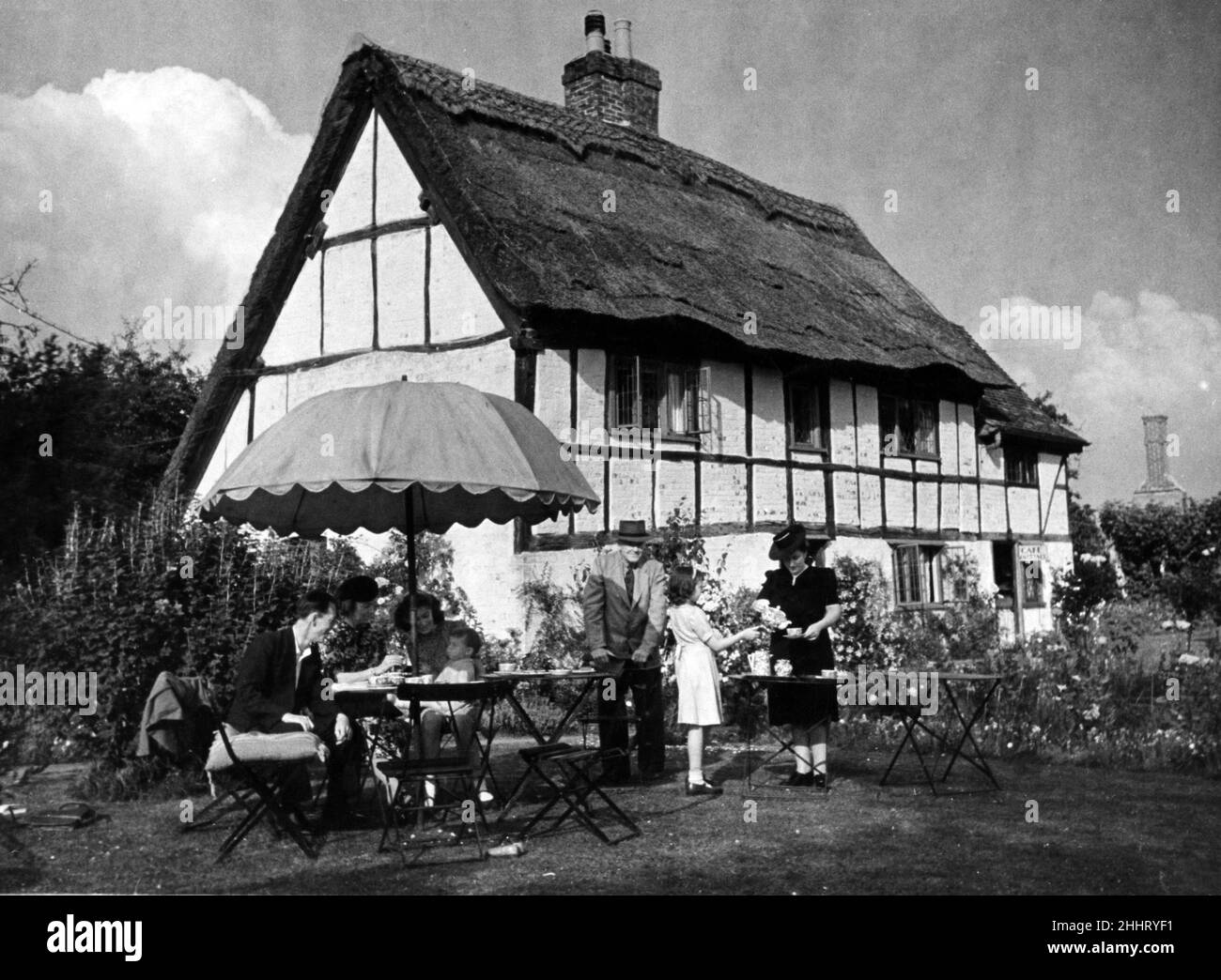 In Whipsnade Village, Bedfordshire, one can take tea at a genuine 15th Century thatched cottage where the gay sunshades lend an old world setting. 24th June 1945. Stock Photo