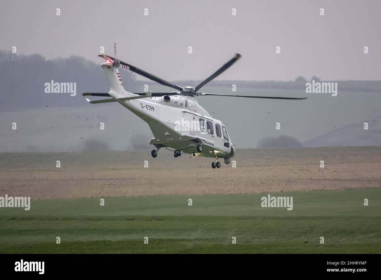 G-ETPP ETPS Agusta AW139 helicopter pitches forwards and ascends from hovering just above grass on a pilot training flight exercise Stock Photo