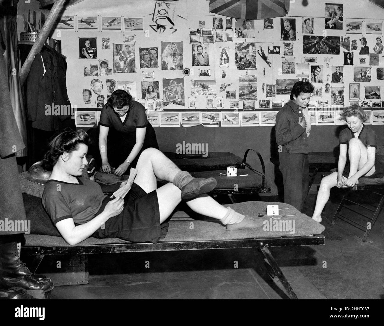 They call it the 'Beehive' ATS girls on a Welsh gun site call their barrack room the 'Beehive'. The walls are covered with pictures of film stars and other celebrities. (Note sketch of Winston at top'. Girls in their picture bedecked room one of whom is dealing with a troublesome corn. January 1943 P014826 Stock Photo