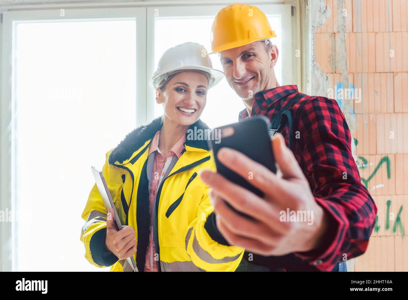Female construction engineer and male worker taking selfie Stock Photo