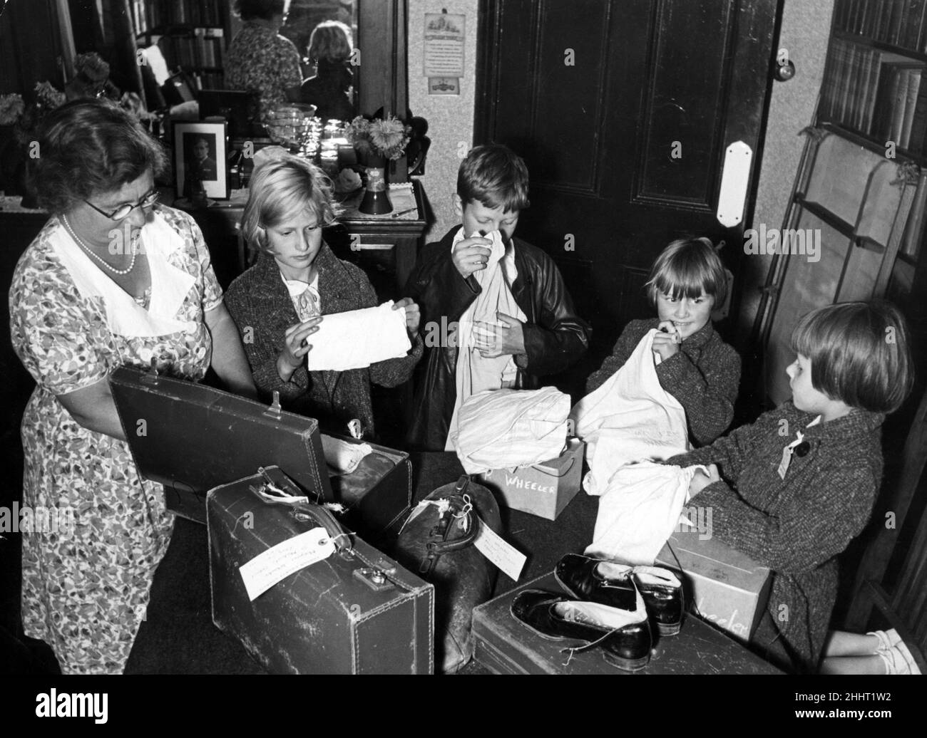 Children of Pimlico, London who attend St Michael's Church School on Buckingham Palace Road, packing for tomorrow's evacuation. The children, Patricia Wheeler, Maureen Wheeler, Teddy Wheeler and Peggy Wheelr are pictured with Mrs Rixson, the wife of the headmaster. 1st September 1939. Stock Photo