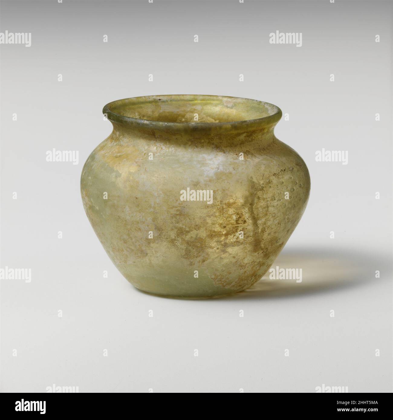 Glass jar 2nd–3rd century A.D. Roman Colorless with pale greenish tinge.Rounded and everted rim; narrow, concave neck; bulbous body, tapering downwards; pushed-in bottom with traces of irregular pontil mark.Intact; some pinprick and larger bubbles; dulling, iridescence, and whitish weathering.. Glass jar  244616 Stock Photo