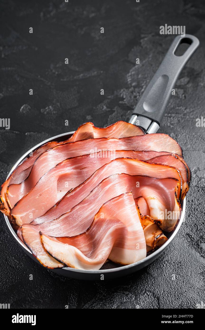 Cooking of Black Forest Ham in skillet. Black background. Top view