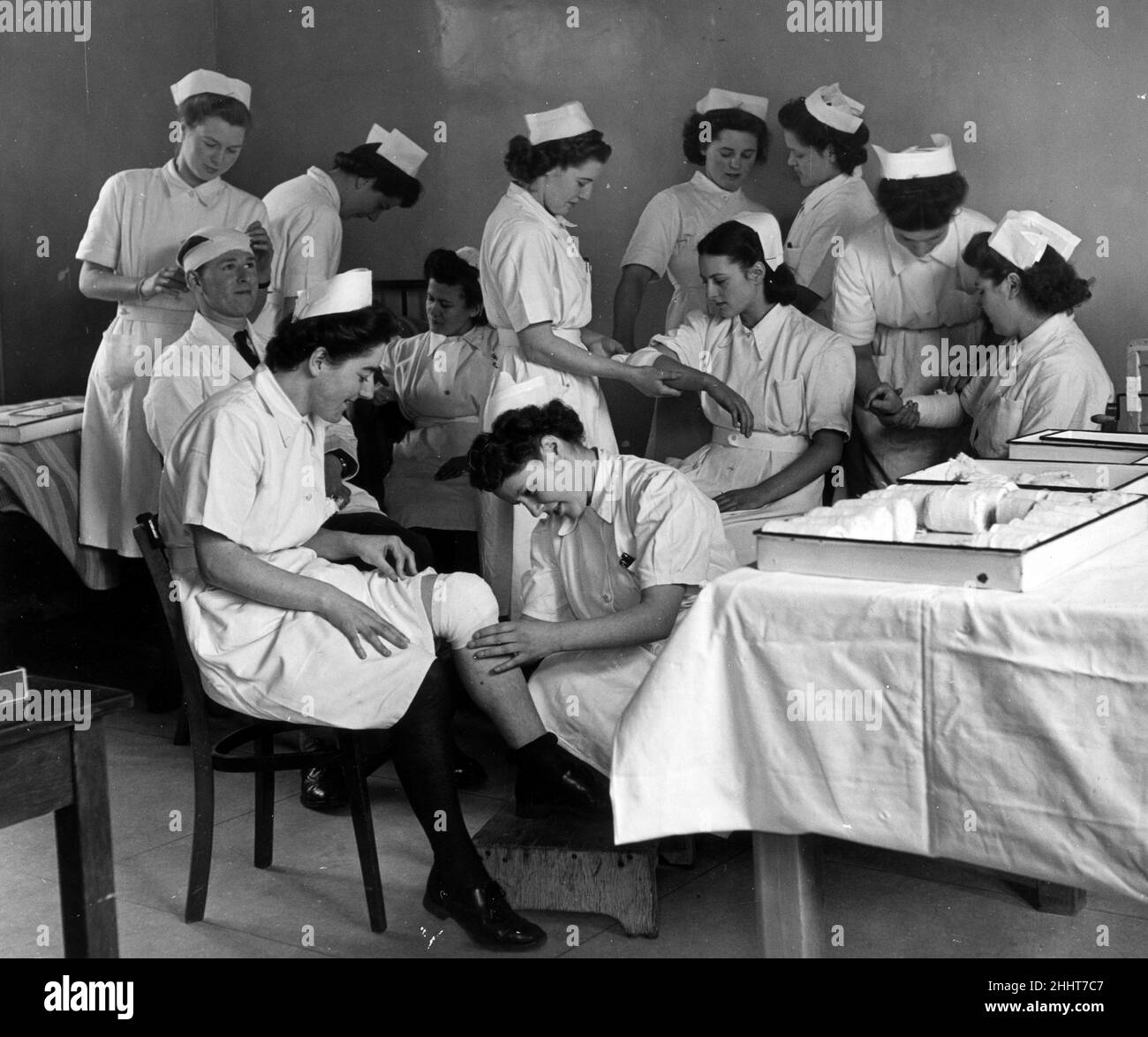 Student nurses of six nationalities learn the art of bandaging by working in pairs aand using each other as subject as they receive basic knowledge of their duties at one of the nine hospitals which are being taken over by the new National Health Scheme at the Central Preliminary Training School in Hadley Common, Hertfordshire.  20th February 1948. Stock Photo