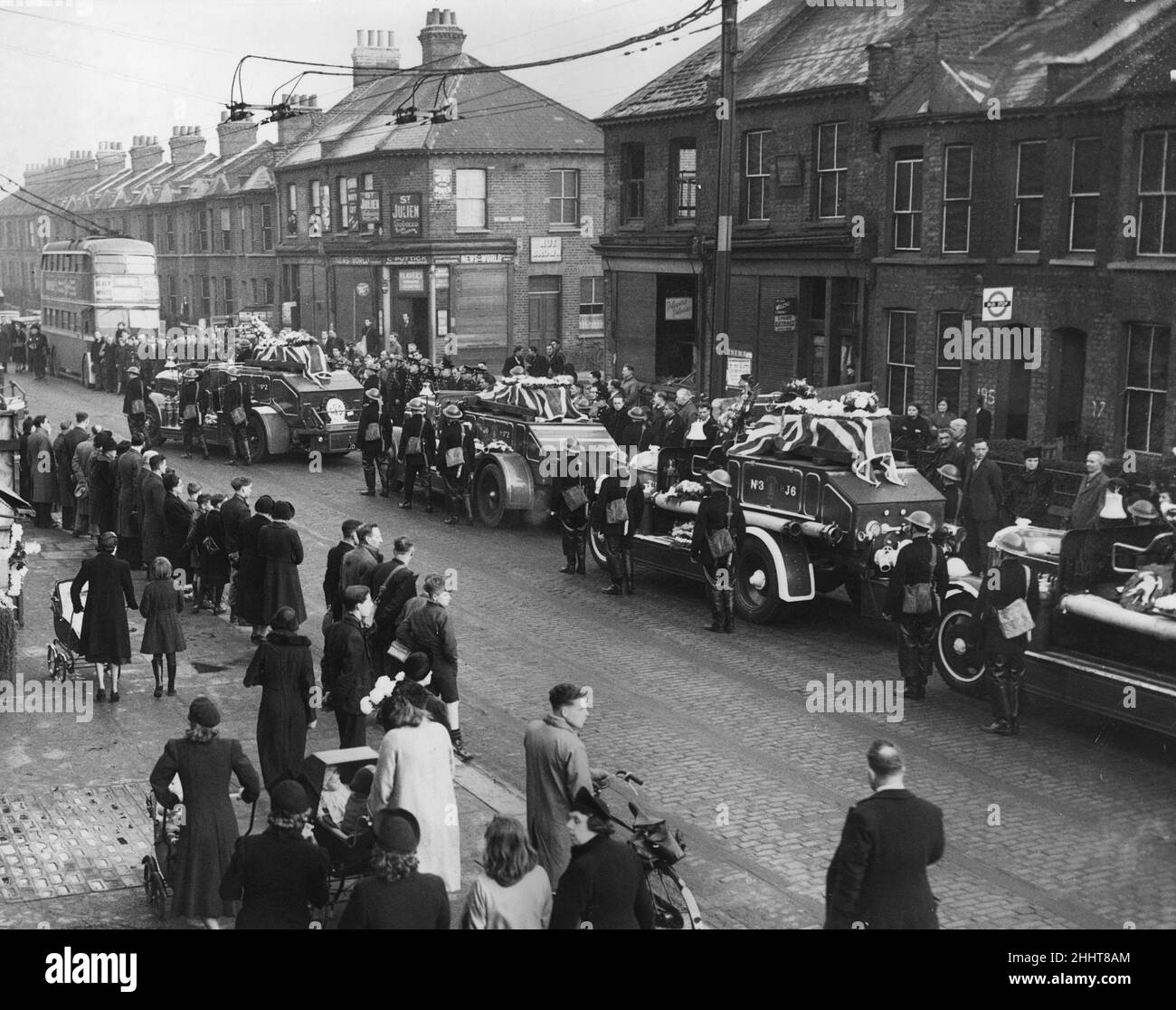 Coffins are draped by Union Jacks borne on fire appliances in procession through Plaistow on the way to the cemetery during the funeral of Plaistow fireman who were killed in the blitz.Circa 1941. Stock Photo