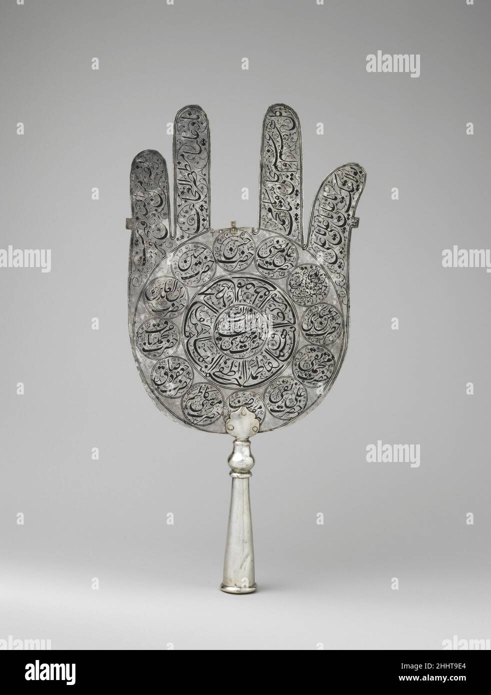Standard early 18th century Under the Ottomans, Safavids, and Mughals, steel or silver standards were used in military, royal, and religious ceremonies. The talismanic power of this standard ('alam) is understood through the choice of the inscriptions. On one side, in the centermost circle, the Shi'i prayer venerates the Prophet Muhammad's family through his cousin and son-in-law 'Ali, his wife Fatima, and their sons Hasan and Husain, supported by the protective Throne verse (2:255). The other side honors the twelve imams, with the name of the twelfth imam enclosed in the central circle. As fo Stock Photo