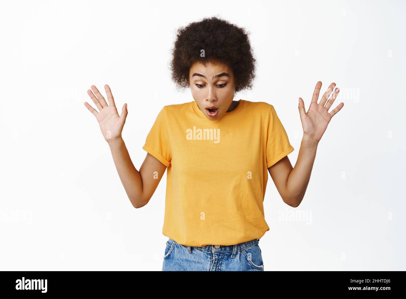 Image of african girl looking down with surprised, startled face