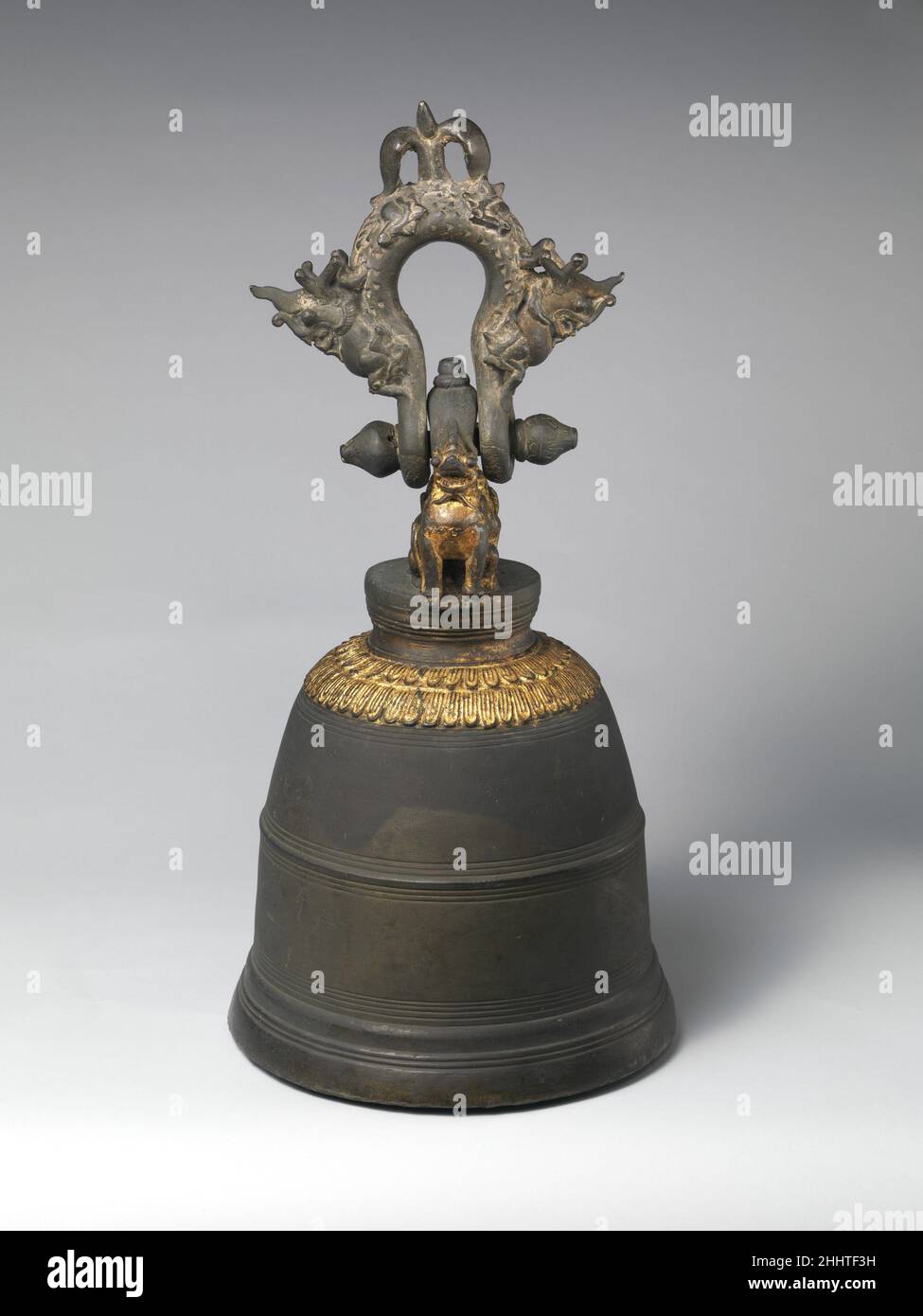 Monastery Bell 1879 Burmese Cast in Shwebo, a town north of Mandalay, this monastery bell weighs approximately one hundred and fifty pounds and is part of an ancient tradition of elaborately adorned clapperless bronze hanging temple bells found throughout Southeast Asia and Indonesia. The support mounts, attached above a stylized and gilded double lotus design appearing on the bell's shoulder, take the form of two guardian simbas (mythical lions), while the suspension loop is cast to represent two makaras (Hindu water monster) whose tails meet to form a finial. On the bell's upper side a barel Stock Photo