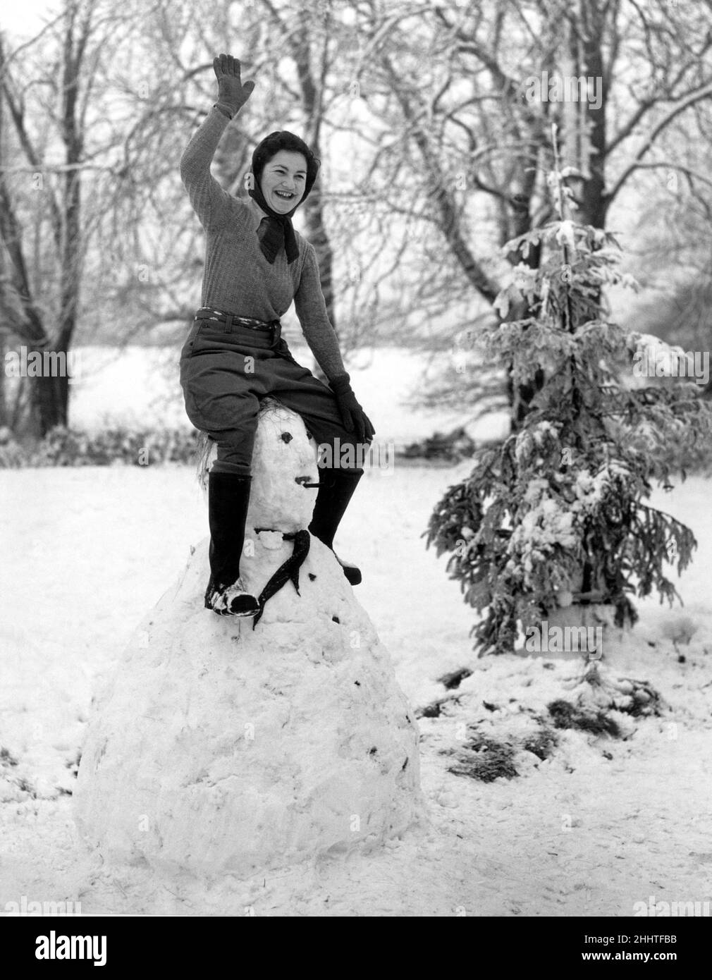 A land army girl in Sussex sitting on top of her Hitler snowman  during the Second World War. 14th January 1942. Stock Photo