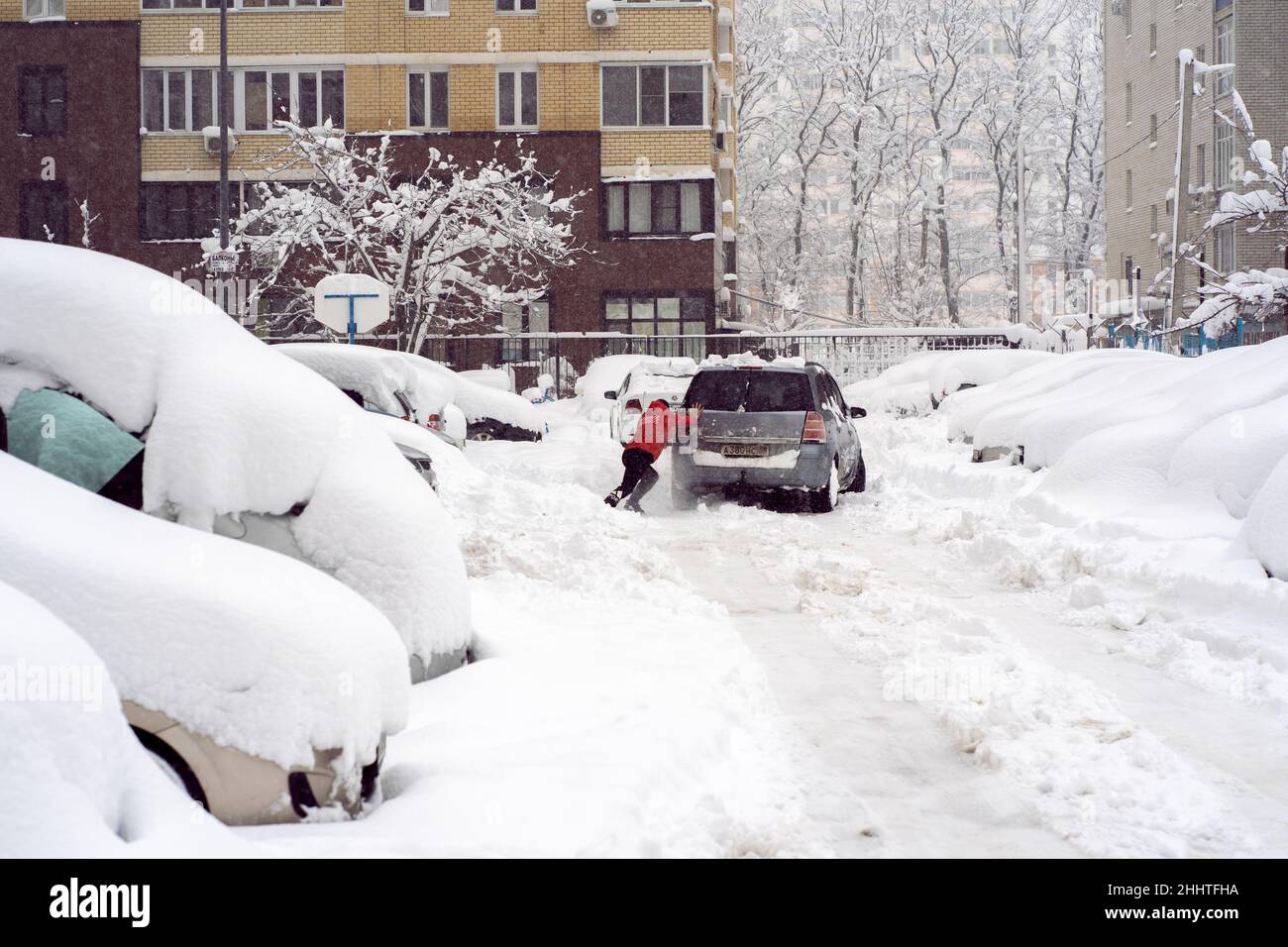 Krasnodar, Russia - January 23 2022: Man Pushing Car On Snow Covered Road Stock Photo