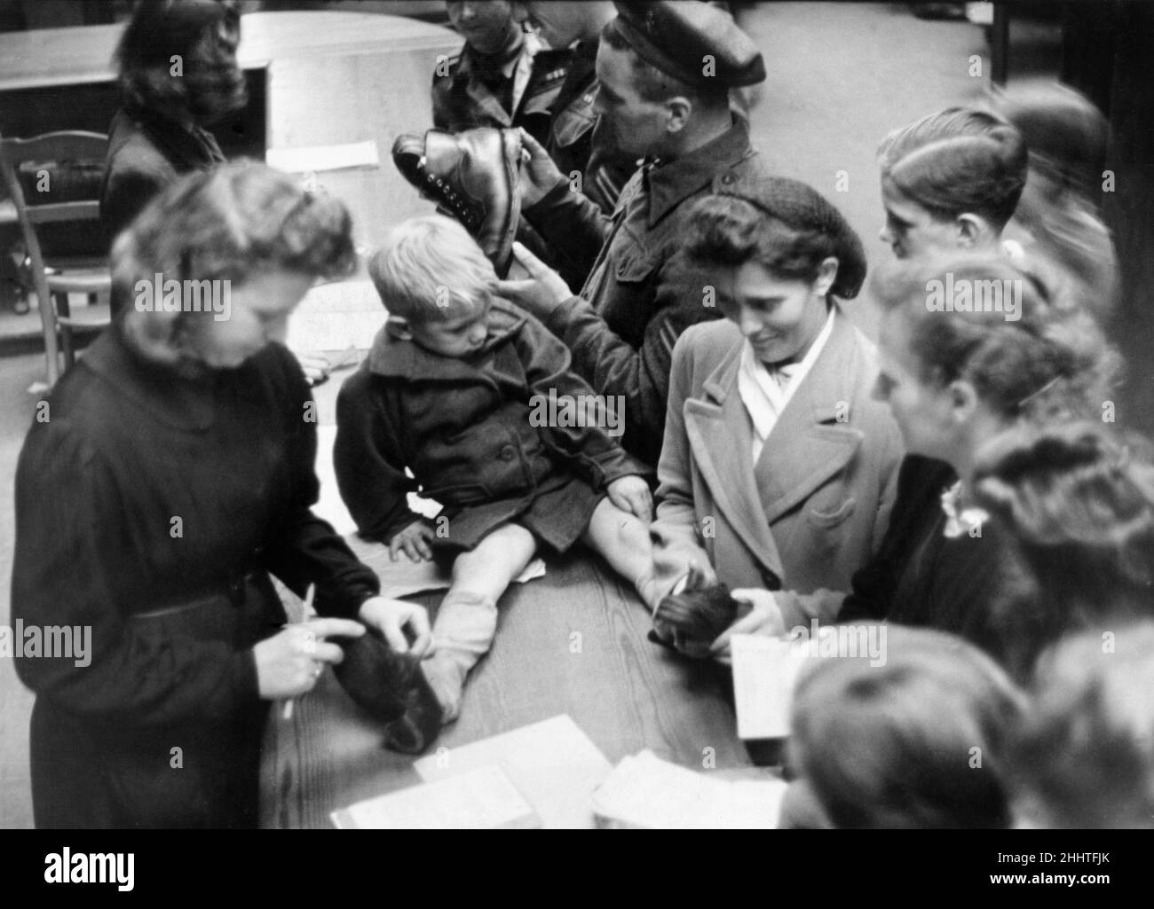 A barter exchange in Luneburg, Germany after the Second World War. After the war there was  a scarcity of vital necessities such as food, clothing and every day commodities such as appliances and household utensils. As none of these were being manufactured the only option left to Germans to acquire these things was through a trade barter.  Picture shows: Frau Schroeder of Luneburg who has siren her vacuum cleaner for two pairs of used shoes for her young son Dietmar (sitting on the counter) and Heidemarie. 2nd October 1945. Stock Photo