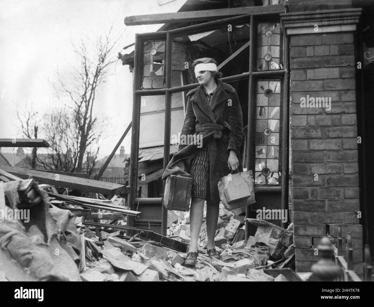 Resident Miss Kitty Connealey, slightly hurt during a German air raid on the city of Hull, emerges from her house with a few personal possessions after it was damaged in the attack. 31st March 1941. Stock Photo
