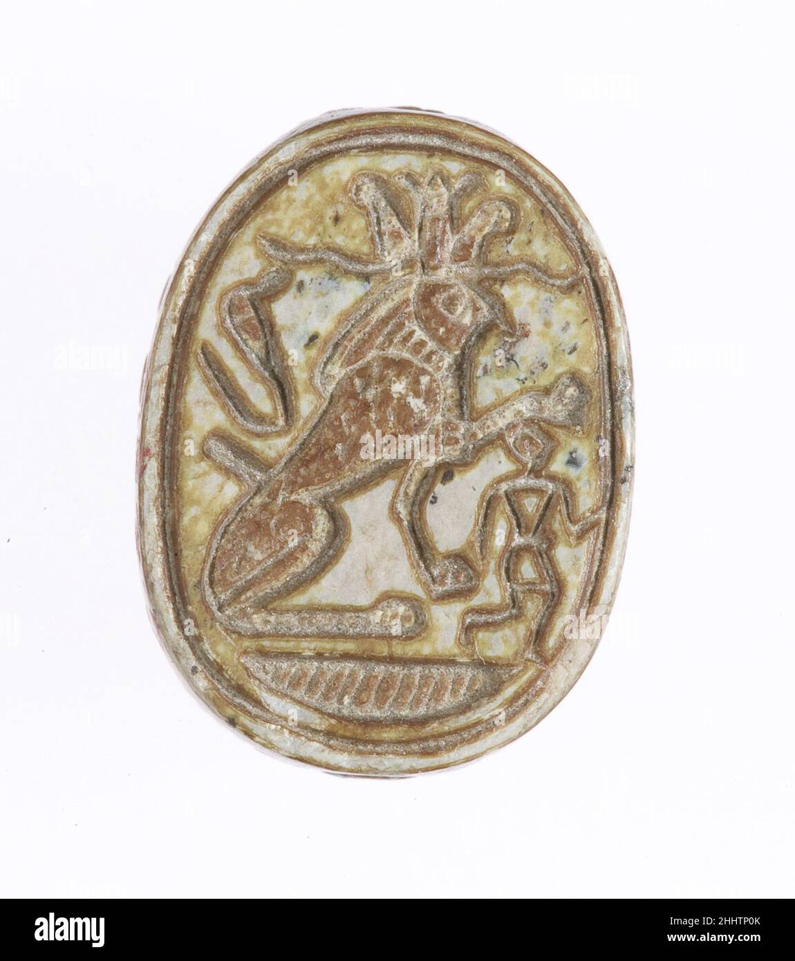 Scarab Inscribed With a Protective Motif ca. 1550–1458 B.C. New Kingdom The scarab's base depicts a falcon-headed sphinx wearing the 'atef' crown while subduing an enemy of Egypt. The falcon represents Re-Harakhty - the god Horus when he is merged with the sun.. Scarab Inscribed With a Protective Motif. ca. 1550–1458 B.C.. Glazed steatite. New Kingdom. From Egypt, Upper Egypt, Thebes, Asasif, Carnarvon/Carter excavations, 1911. Dynasty 18, early Stock Photo