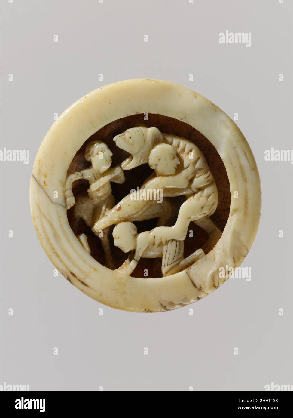 Game Piece with Menelaus and Companions Battling Proteus ca. 1125–50 North French Objects related to the games of tables and chess were among Salgo’s favorite items. Such games were predecessors of modern backgammon and widespread in Medieval Europe. Surviving ivory game pieces are rare, and this is the only known piece from a thirty-piece set. These unusual objects often depict sophisticated narrative and allegorical subjects. This carving may show a scene from the Odyssey, when King Menelaus drives a spear into the open jaws of the sea-god Proteus, transformed into a lioness or bearlike crea Stock Photo