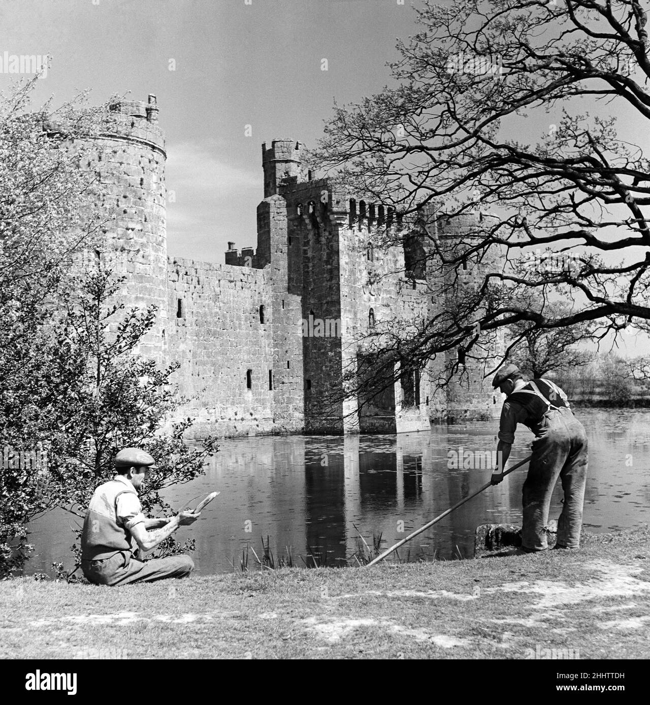 A groundkeeper cleaning the moat outside Bodiam Castle, a 14th-century moated castle near Robertsbridge in East Sussex. 5th May 1952. Stock Photo