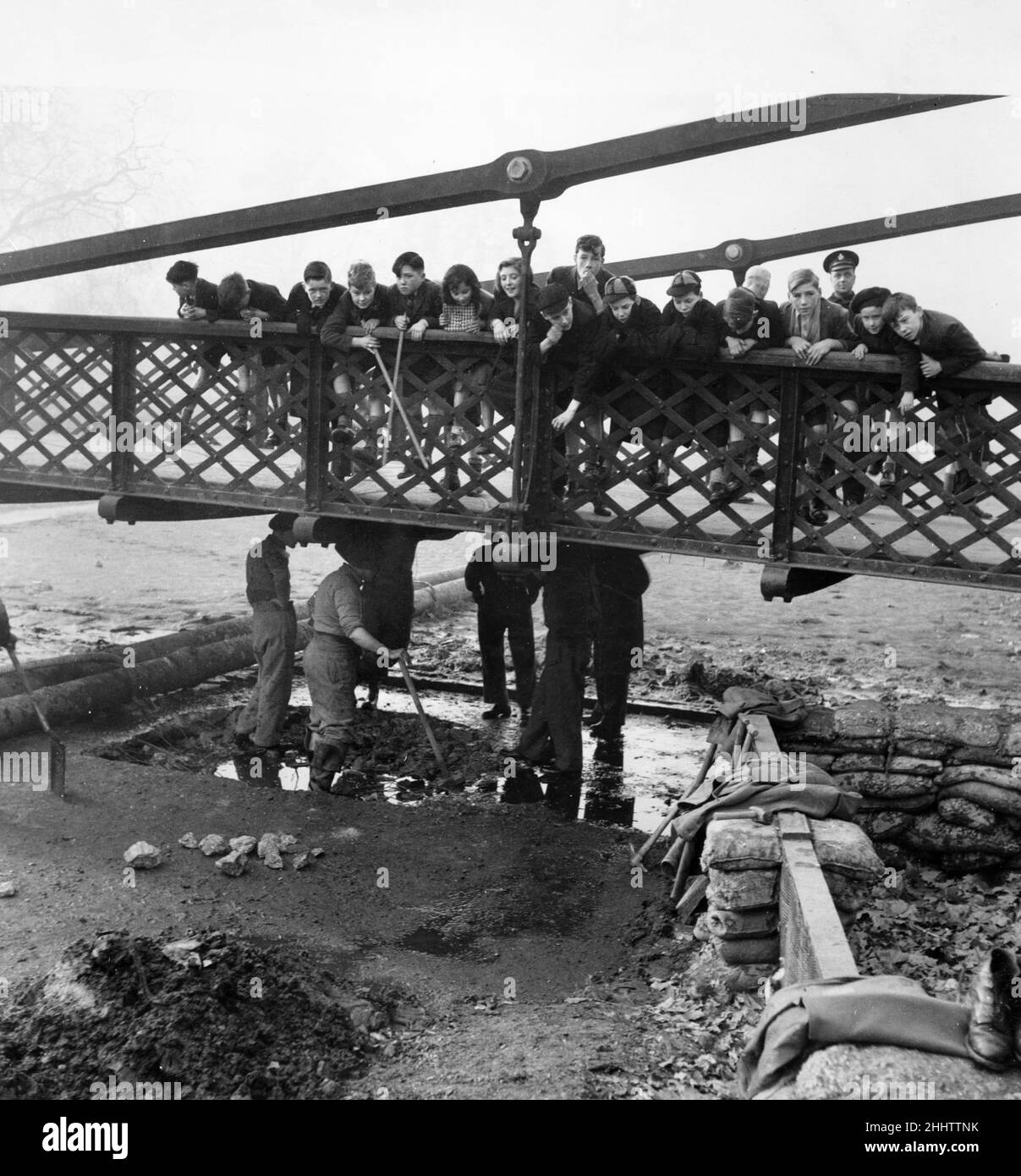 Brtitish Army soldiers of the Royal Engineers undertake a bomb disposal at St James Park, LondonPicture shows: Sappers excavating the land for the 1000 lb bomb believed to be embedded between 20 to 30 feet under the river bed.  Young schoolchildren watch the ongoing excitement below from a bridge across the lake of the park.  6th February 1946. Stock Photo