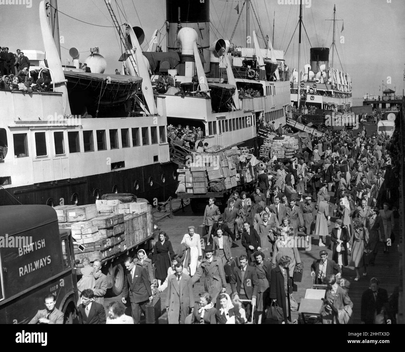 Holidaymakers returning from the Isle of Man make their way along Liverpool landing stage from the steamer ship Mona Isle. The Ben My chree ship behind loads up to take another shipful for their holiday, Merseyside. 4th August 1951 Stock Photo