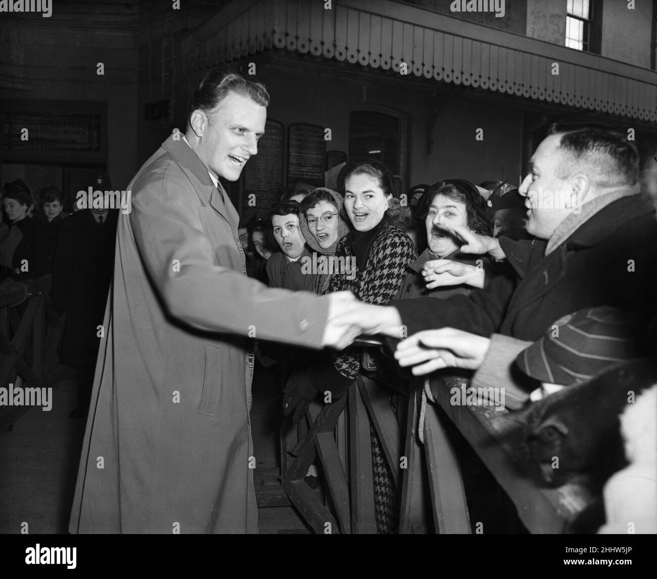 American evangelist Billy Graham salutes the huge crowd who gathered to welcome him at Plymouth Dock Gates after his arrival from the French liner Liberte. 18th March 1955. Stock Photo