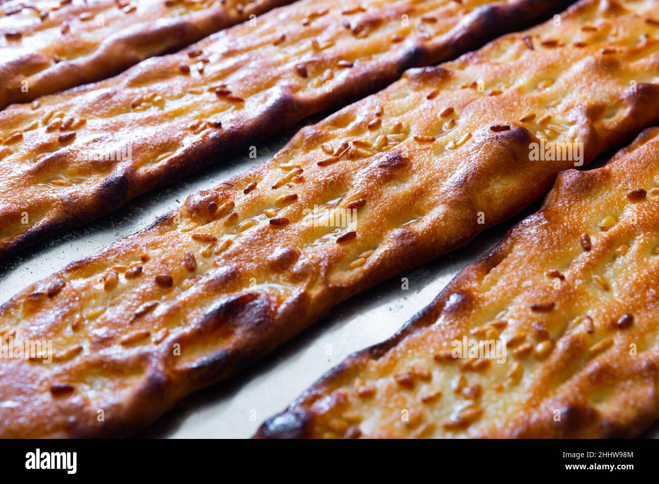 Closeup of freshly baked cocas with sesame on steel surface Stock Photo