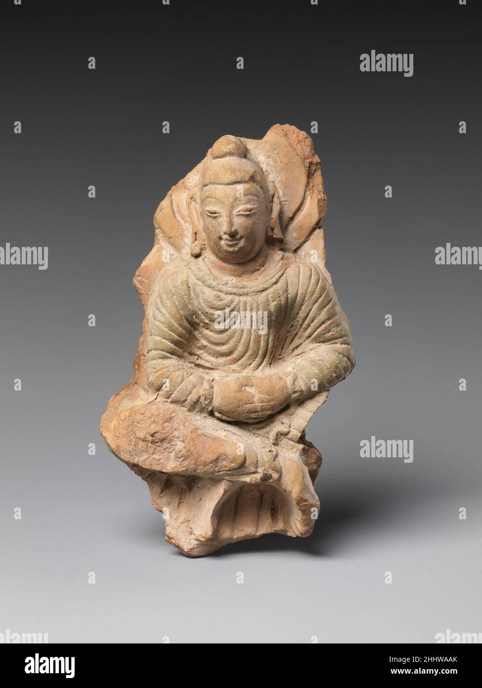 Seated Buddha 6th–7th century China (Xinjiang Autonomous Region) This Buddha image was using a mold. It exemplifies the Khotan taste for Gandharan classical drapery—here, juxtaposed with the local aesthetic, as seen in the representation of the face and hair.. Seated Buddha  39980 Stock Photo