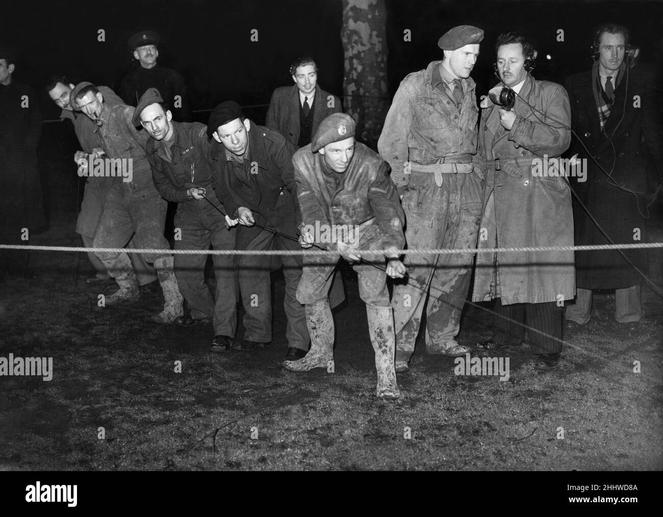 Brtitish Army soldiers of the Royal Engineers undertake a  bomb disposal at St James Park, London.Picture shows: Sappers pulling on the fail cord in the park whilst Lieutenant Hilton and Wilfred Vaughan Thomas of the BBC give a running commentary on the radio. 6th February 1946. Stock Photo