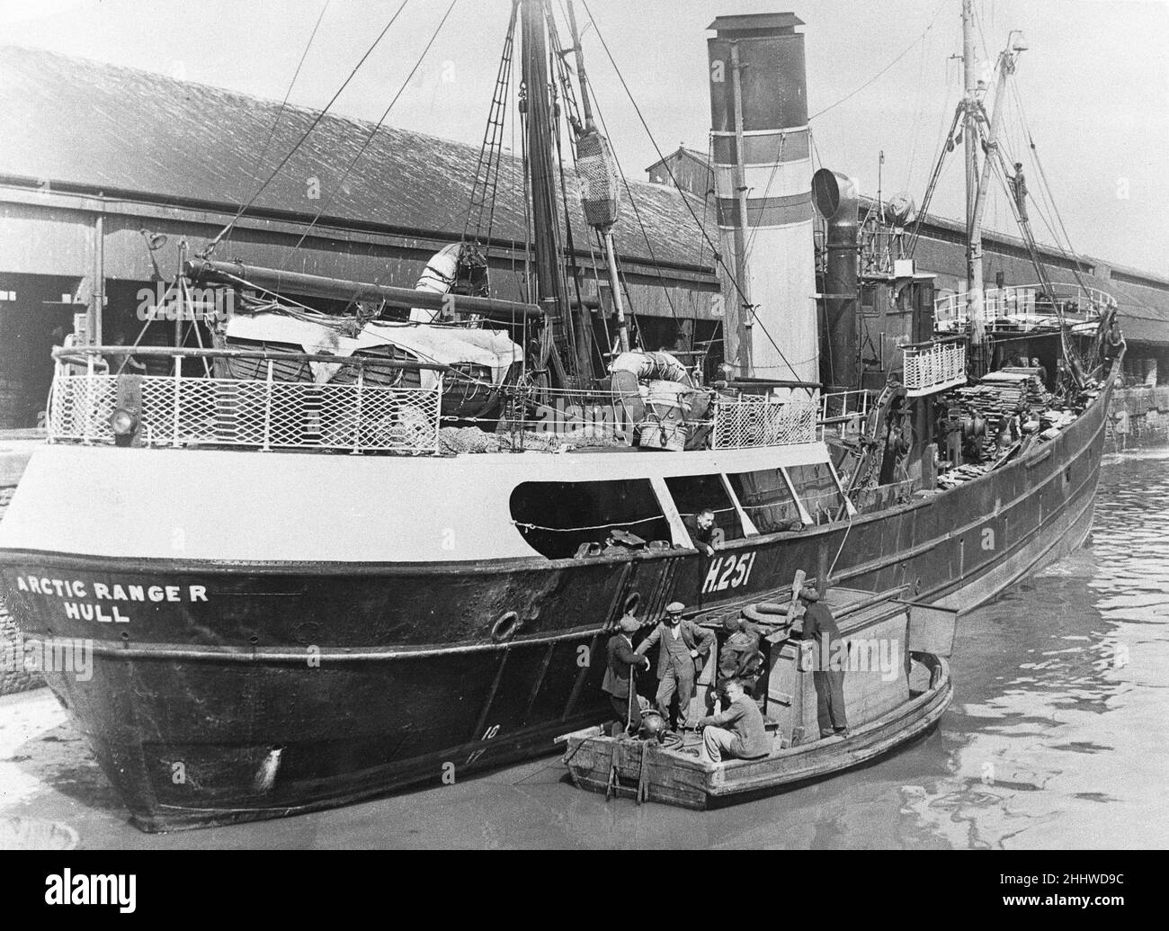 The crew of a diving boat chat with a crew member of the Boyd Line Ltd sidewinder trawler Arctic Ranger  as she lay alongside St Andrews Dock, Hull. Circa June 1948 Stock Photo