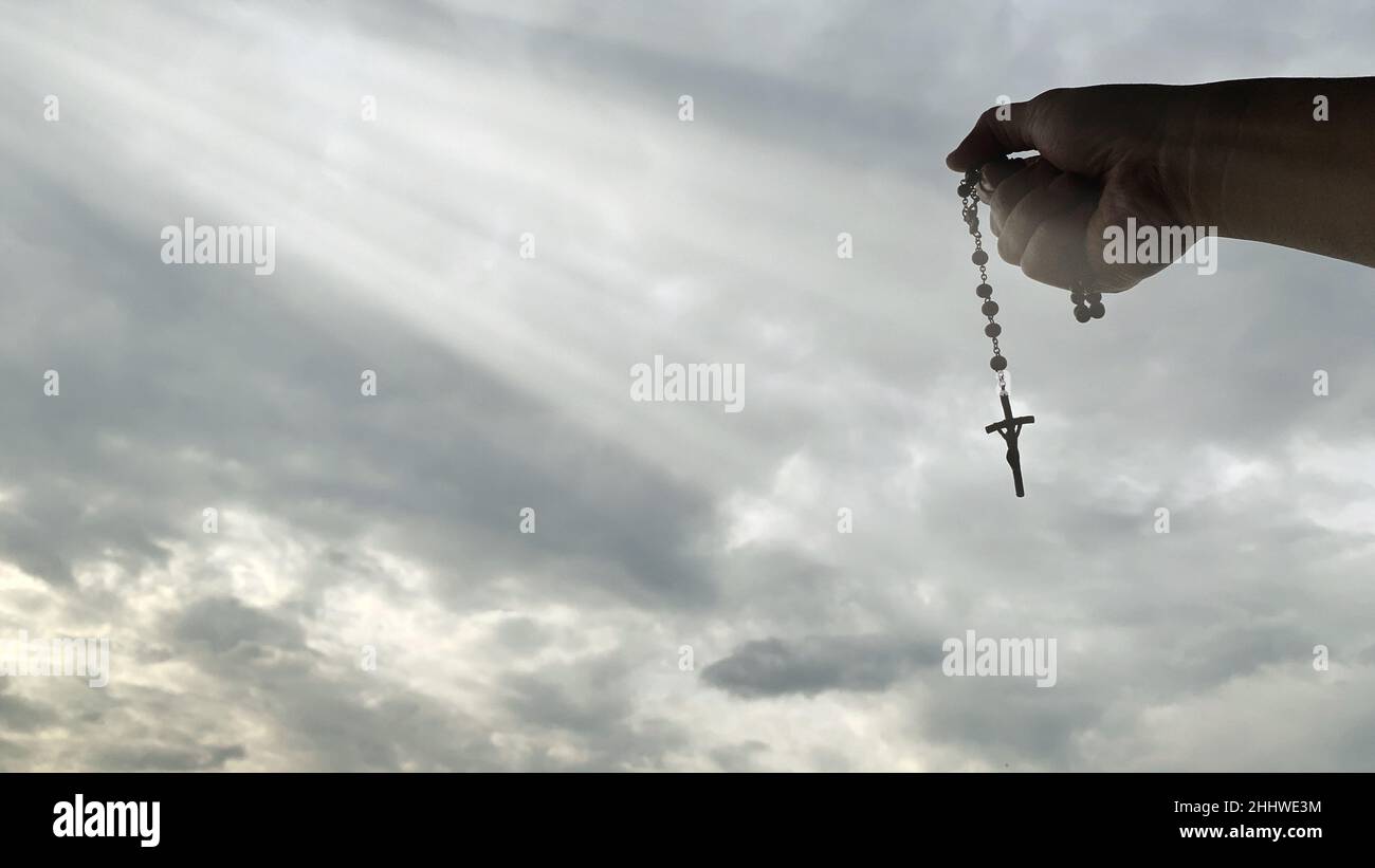 Bright shining light with hand holding Holy Rosary. Christianity concept. Stock Photo