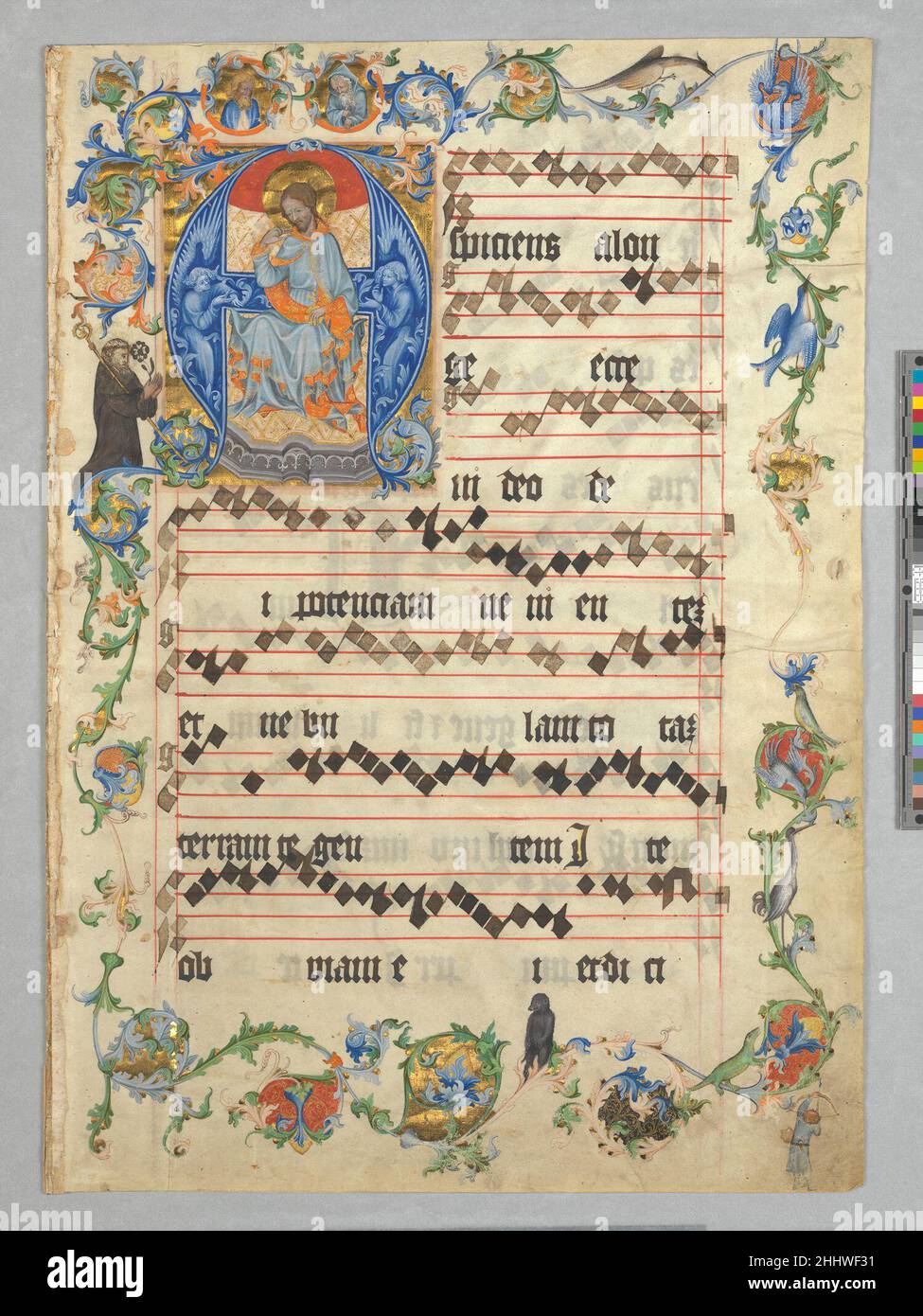 Bifolium with Christ in Majesty in an Initial A, from an Antiphonary ca. 1405 Bohemian With rich color and gold, this leaf from a choir book joins majesty and mystery with a sense of playfulness. The letter A becomes a throne for Christ, robed in silks, as he sits before a cloth of gold held by barely perceptible crimson angels. Meanwhile, in the margins, a gentle black bear perches on a vine; nearby is a lizard and a hunter aiming his arrow at a crane. This was the first page of a richly decorated book of hymns. The text set to music here was sung on the first Sunday of Advent, the season pre Stock Photo