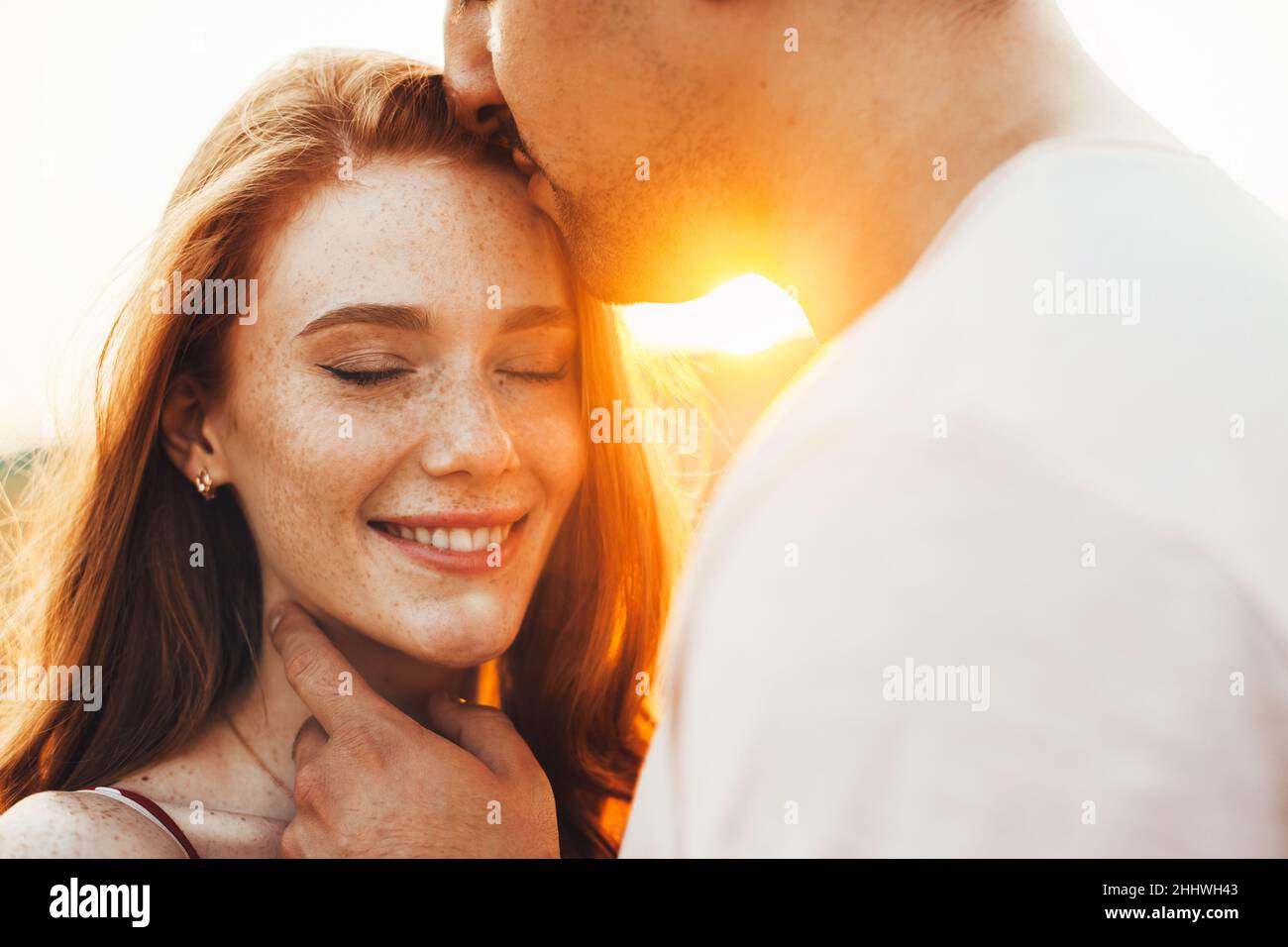 Freckled woman smiling as she is kissed on the forehead by her boyfriend's lips. Beautiful couple embracing on a road travel, great design for any Stock Photo