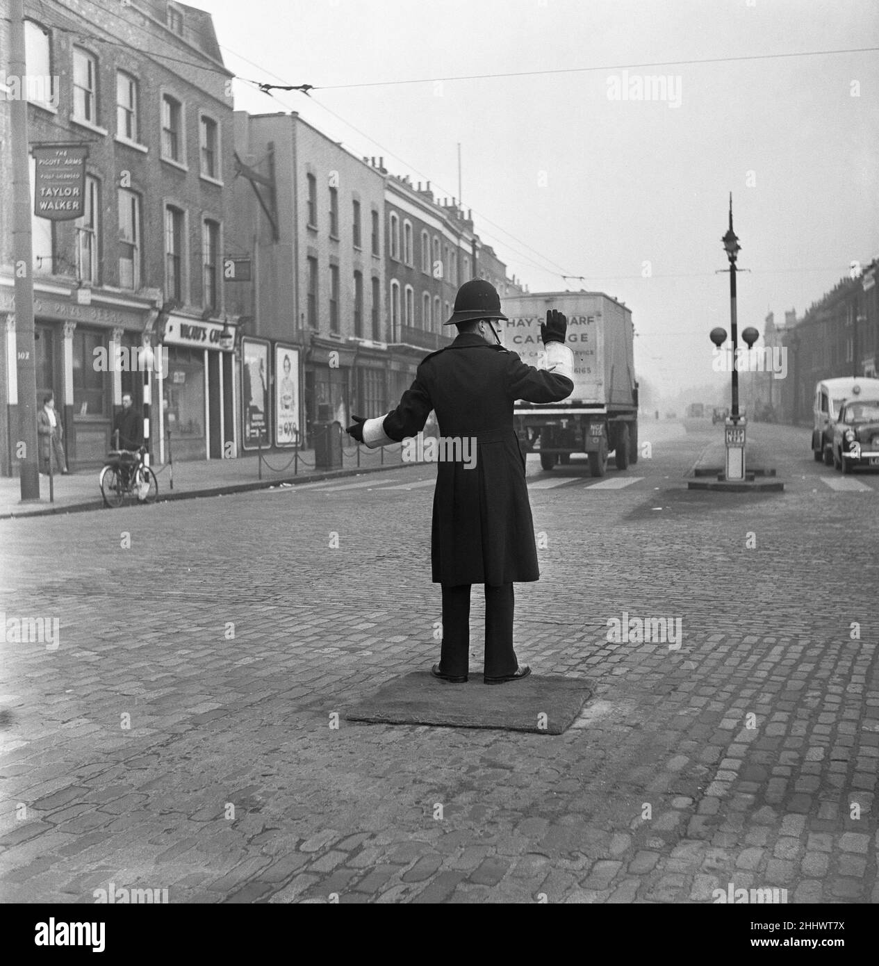 A policeman on point duty at the junction of Commercial Road with the junction of East India Dock Road and West India Dock Road, stands on a mat. 11th January 1954 Stock Photo