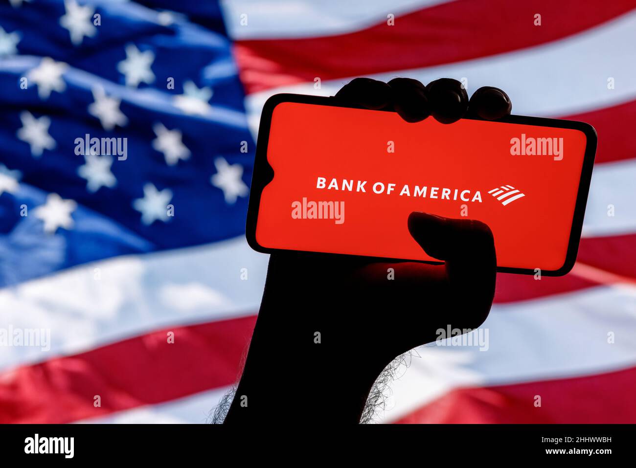 Smartphone with Bank of America logo in clenched hand on background of