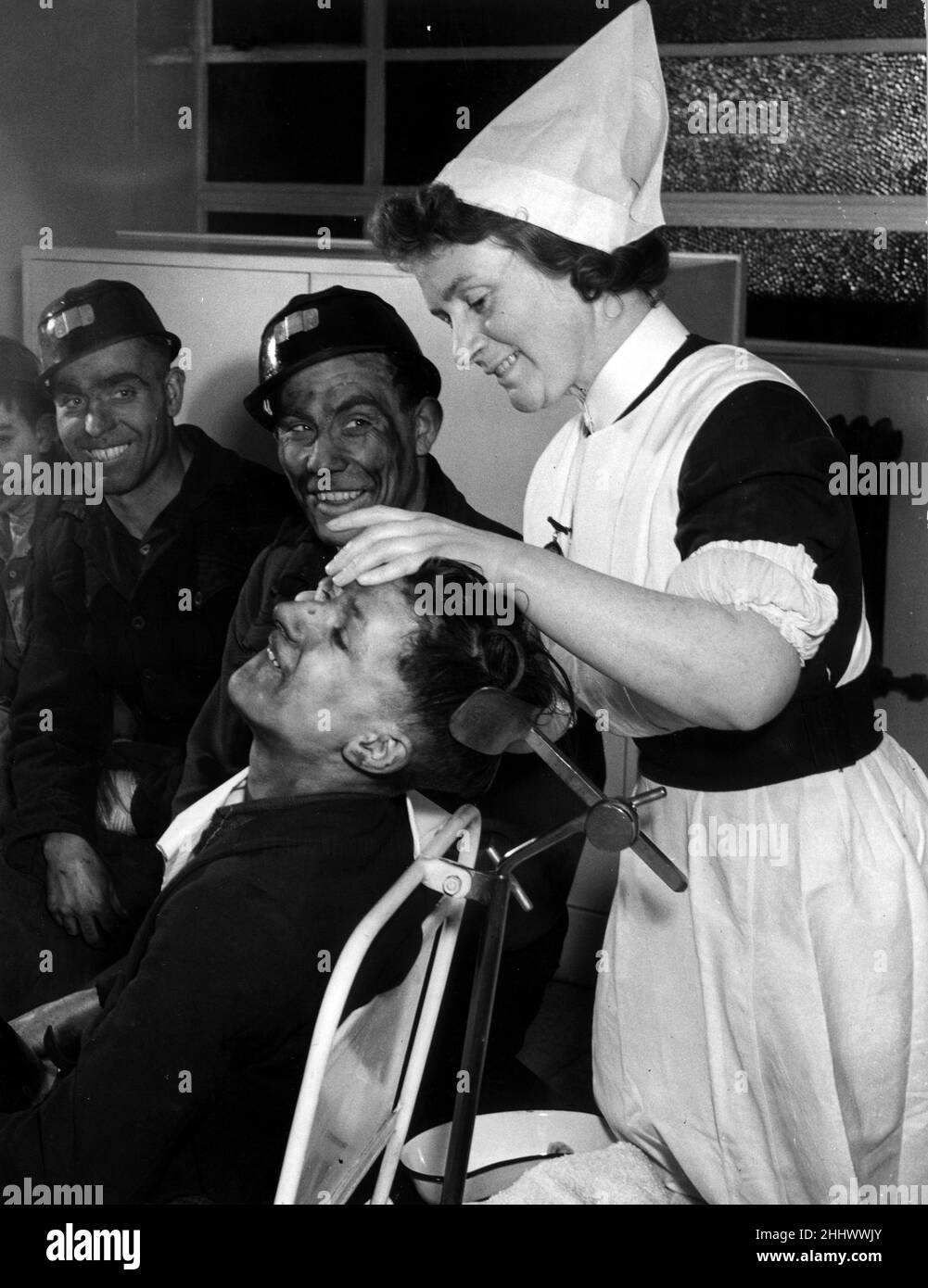 Sister Ada Starkey, one of the thirty four nurses helping to give miners a proper nursing service at the pithead, attending to sixteen year old coal miner Cyril Ainsworth at Church Gresley in Derbyshire. 12th January 1948. Stock Photo