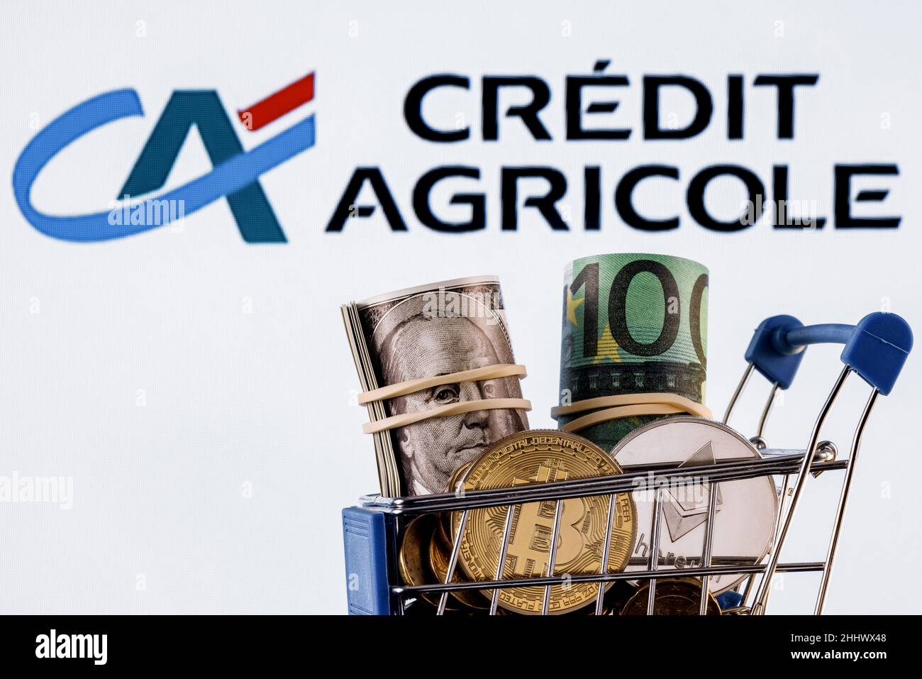 Crypto and traditional currencies in shopping cart on background of Credit Agricole bank logo Stock Photo