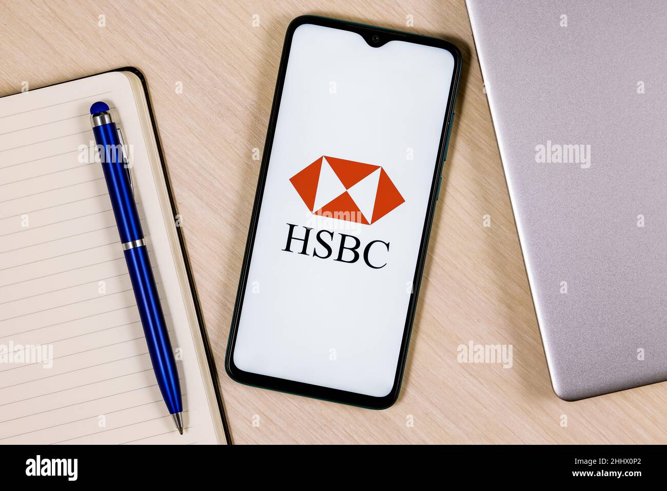 Smartphone with HSBC bank logo on wooden table next to laptop and business planner Stock Photo