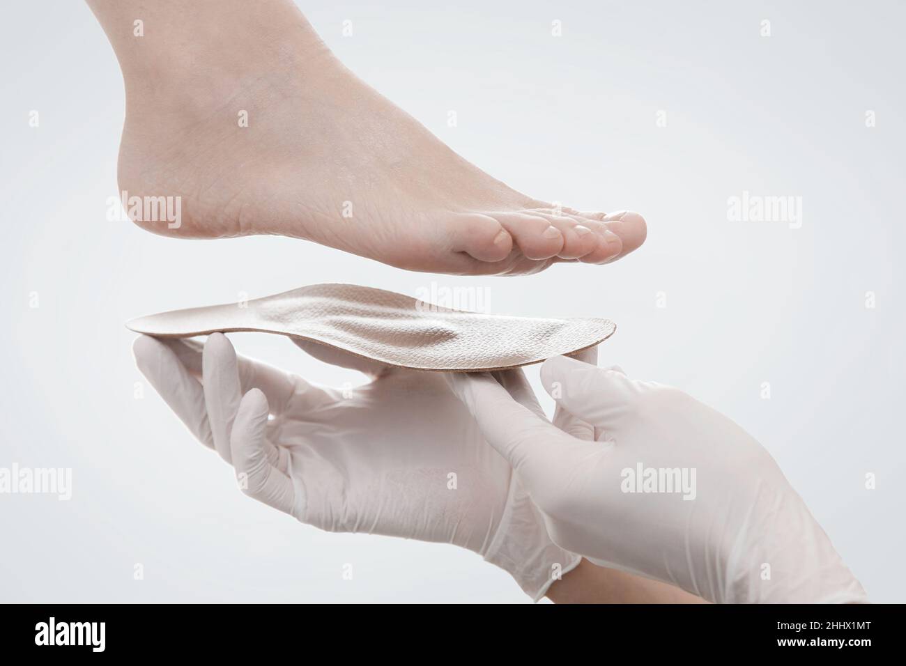 Orthopedic insole isolated on a white background. Hands in rubber gloves hold an orthopedic