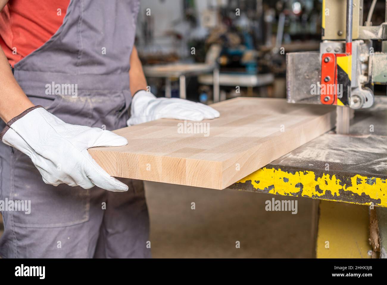 Carpenter cutting wooden board on band saw in joinery Stock