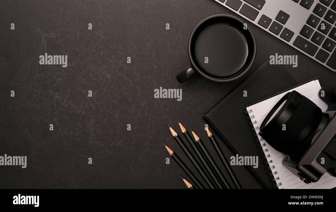 Modern black office desk with stationery, camera, keyboard, coffee cup and copy space for your product display over black background. top view Stock Photo