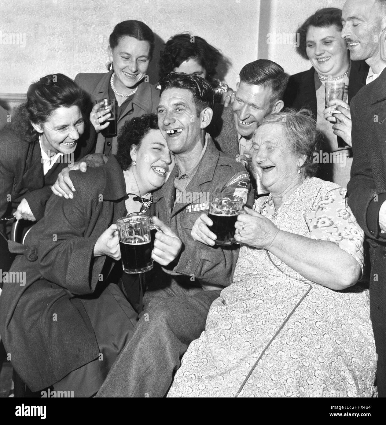 British Prisoners of war released from Korea, pictured on their return to England after docking at Southampton on the Asturius.Private Thomas Nugent of the Gloucester regiment celebrates his return with family at their local pub in Edmonton, North London.  His mother (right) looks on with joy as Tommy hugs his wife Violet. 16th September 1953. Stock Photo