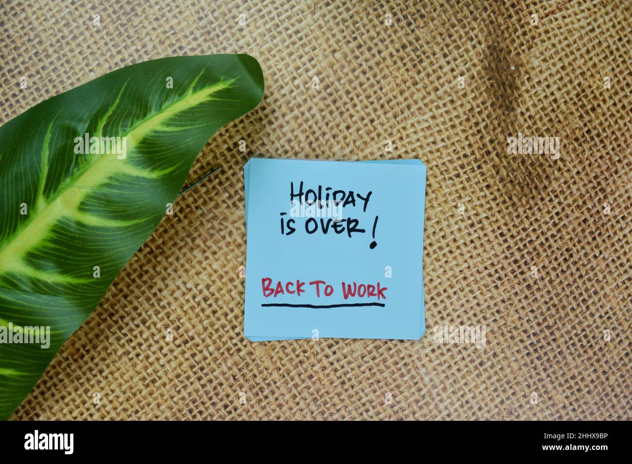 Holiday is Over! - Back To Work write on sticky notes isolated on Wooden Table. Stock Photo