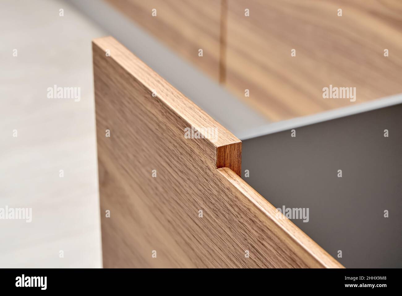 Open drawer of dark grey color with facade of walnut wood with finger pull design in contemporary kitchen extreme close-up Stock Photo
