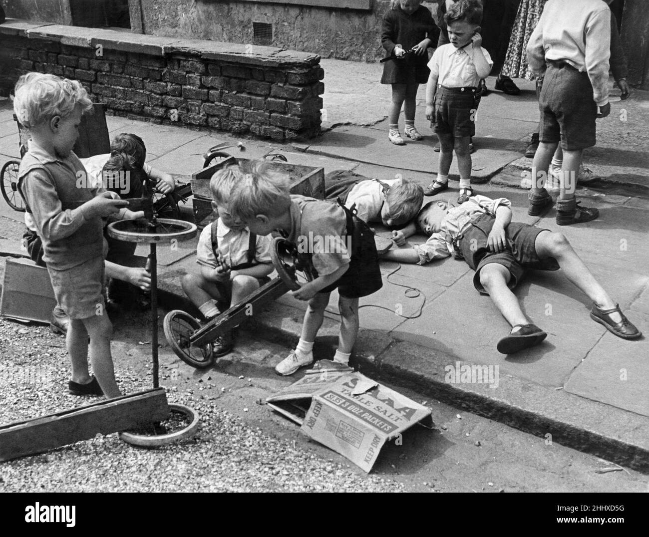 London children prepare for 'Soap Box Derby' June 1950.  A number of soap box Derby races are being arranged for London and provincial towns by several organizations.   Many scouts will take part and an artist at Boreham Wood is helping boys who will test their trollies on a course he has selected.   These small kiddies of Finsbury Park are going to have their own Derby. As soap boxes are in short supply they are getting material and old pram wheels form direlect sites to build their boxes on wheels. Stock Photo