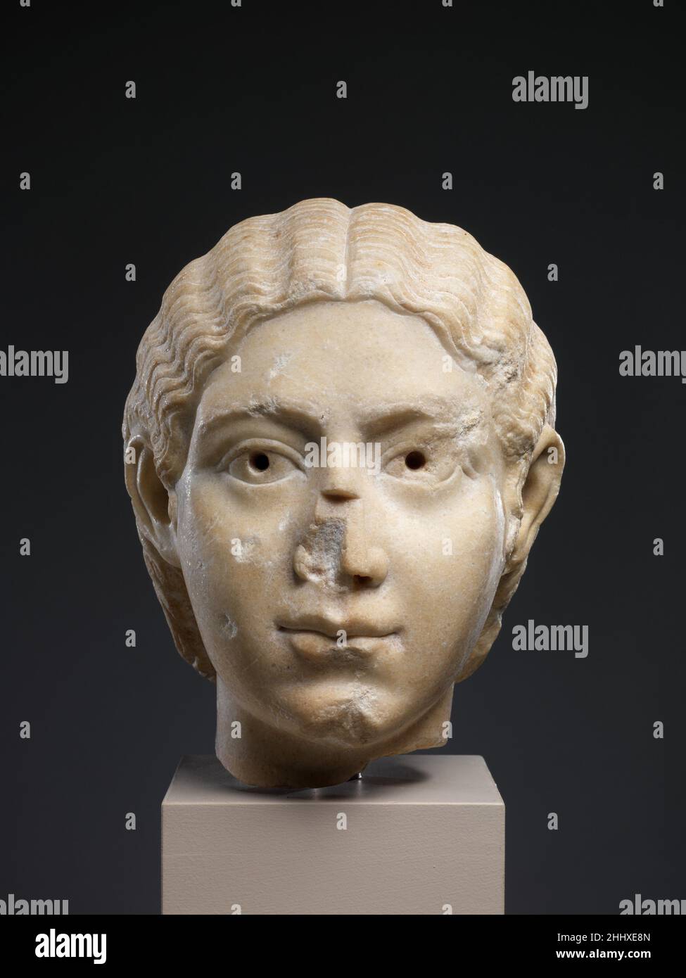 Marble portrait head of a woman ca. A.D. 220–235 Roman The hairstyle follows a fashion set by the Severan court in the early third century. The pupils of the eyes were originally inset; the nose was broken and restored in antiquity.. Marble portrait head of a woman  256758 Stock Photo