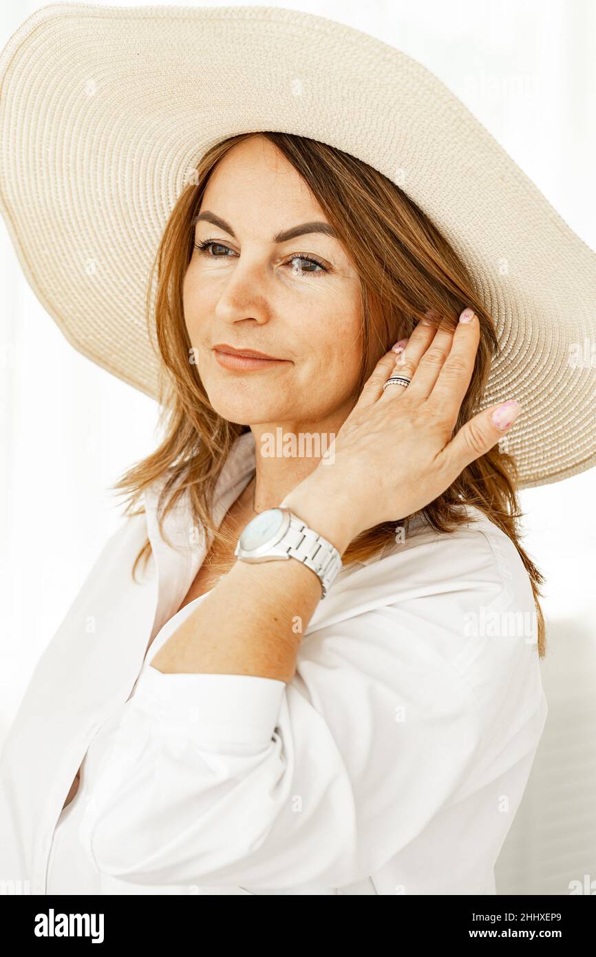 Portrait of a beautiful middle-aged woman in a straw hat. Close-up. Vertical shot Stock Photo