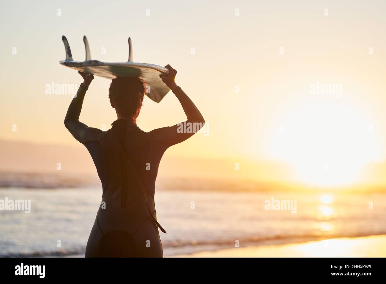 Surfing Is A Way Of Life Rearview Shot Of A Female Surfer Carrying Her Surfboard Over Her Head