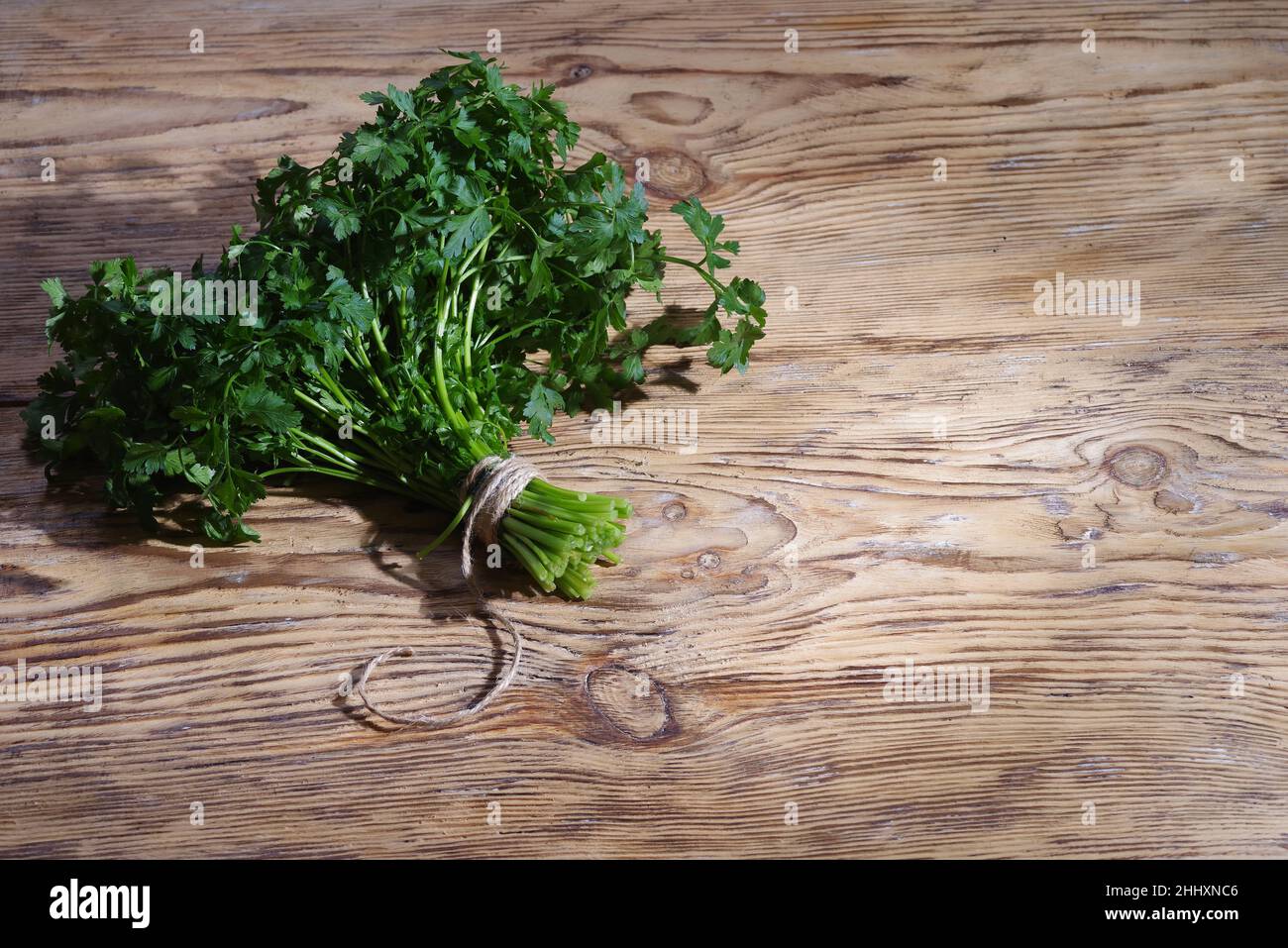 Parsley on wooden table background. Fresh raw parsley plant top view. Parsley indispensable source of vitamins A, C, K, B1, B2, PP, E, C Stock Photo